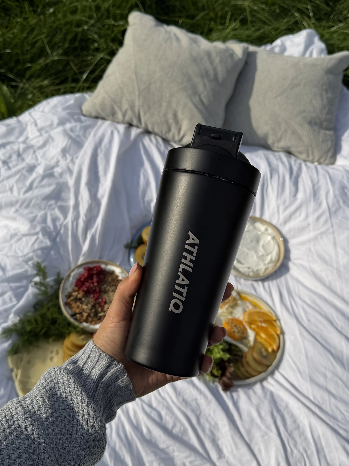 ATHLATIQ Edelstahl Shaker in der Hand beim Picknick