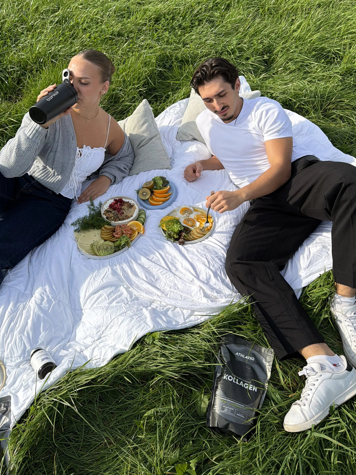 Paar beim Picknick auf einer Wiese mit ATHLATIQ Shaker und Kollagen